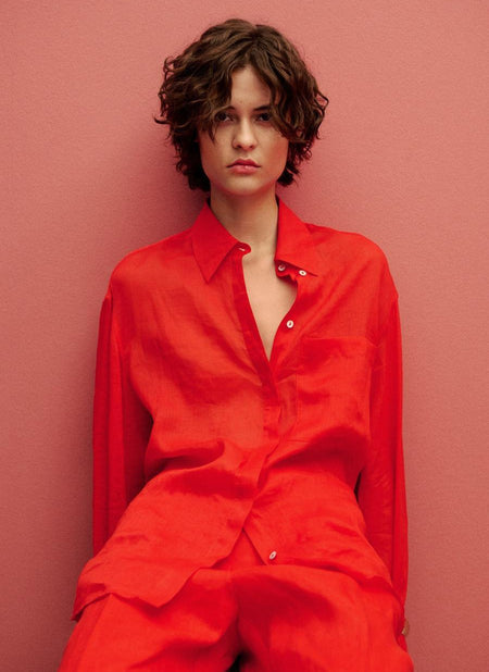 Rood overhemd met lange mouwen van MANGO, van getextureerd linnen, gedragen open over een bijpassende roze achtergrond.