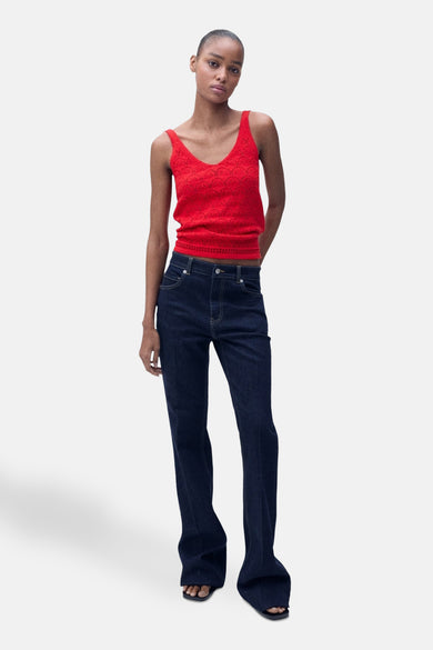 Rood mouwloos topje van MANGO, met ajourpatroon, gedragen met een donkerblauwe high-waist jeans.
