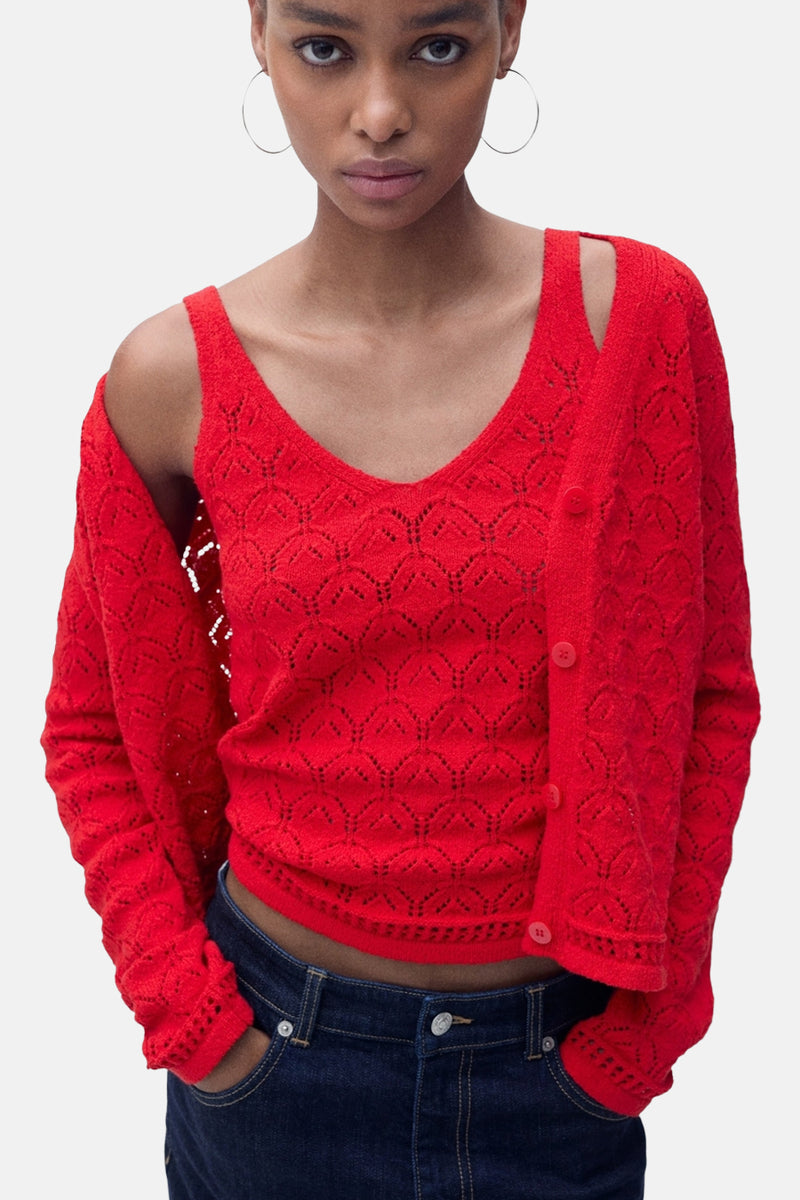 Rood mouwloos topje van MANGO in opengebreide stof, gedragen met een bijpassende cardigan en donkere jeans.