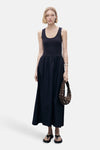 Marineblauwe jurk van MANGO, met een losse pasvorm en een gladde textuur, gedragen met een bruine handtas met studs.