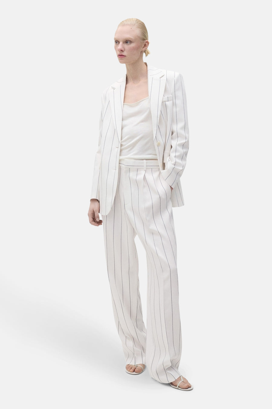 Pantalon de costume blanc de MANGO, à rayures, coupe ample et jambe large, porté avec un débardeur.
