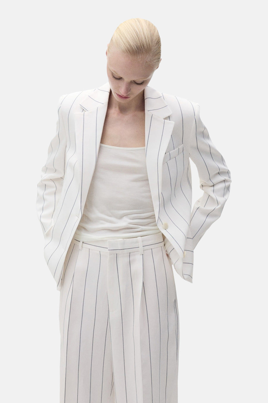 Pantalon de costume blanc de MANGO, à rayures verticales, porté avec un débardeur blanc et une veste assortie.

