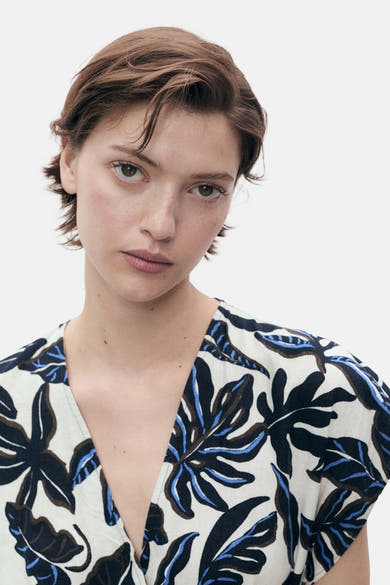Multikleurig pak van MANGO, met een blauwe, bruine en zwarte bloemenprint op een witte achtergrond.
