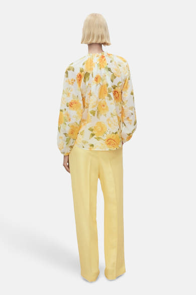 Multikleurige blouse met lange mouwen van MANGO, met geel en groen bloemenpatroon, gedragen met een gele broek.