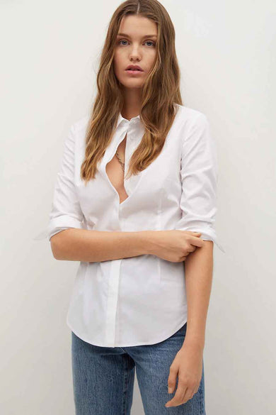 Chemise à manches longues blanche de MANGO, portée avec un jean et un collier.