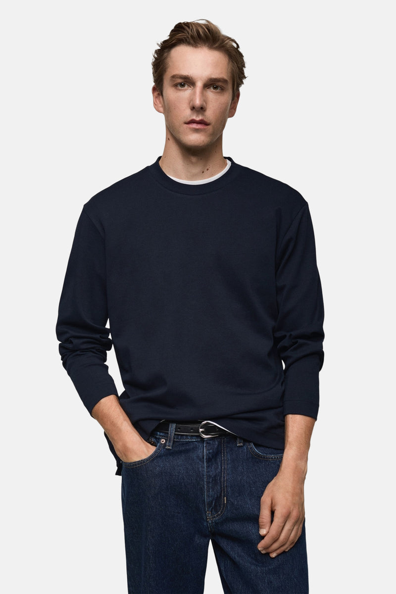 Blauwe T-shirt met lange mouwen van MANGO, gedragen met een spijkerbroek en zwarte schoenen, achtergezicht.