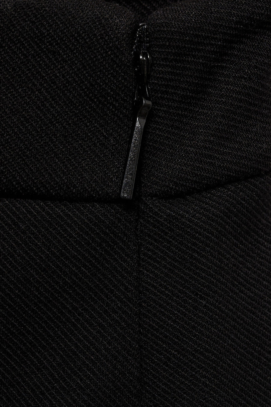 Zwarte broek van MANGO, textuurdetail van de stof met zichtbare ritssluiting.