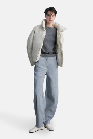 Grijze ronde nekpullover van MANGO, gedragen met een opgevouwen jas en een hoge taille pantalon.