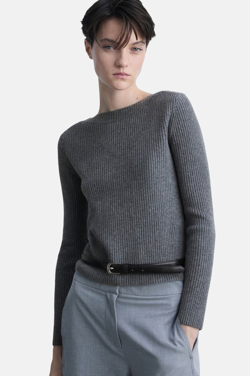 Grijze ronde nekpullover vanANGOANGO, met met een zwarteenur op een donge blauwe broek.