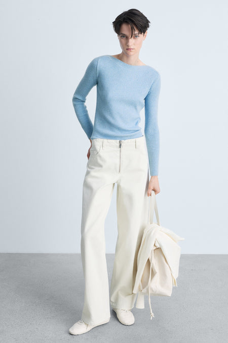 Ronde hals trui van MANGO in blauw, geribbelde gebreide stof, gedragen met een witte broek met ritssluiting.