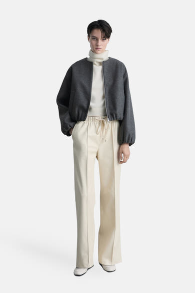 Blazer gris by MANGO, porté sur un pull à col roulé écru et un pantalon taille haute beige.