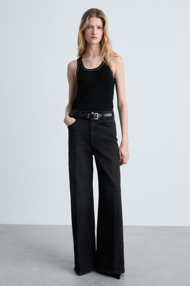 Zwart hemdje van MANGO, met contrasterende biesjes, gedragen met een high-waisted jeans en een zwarte riem.