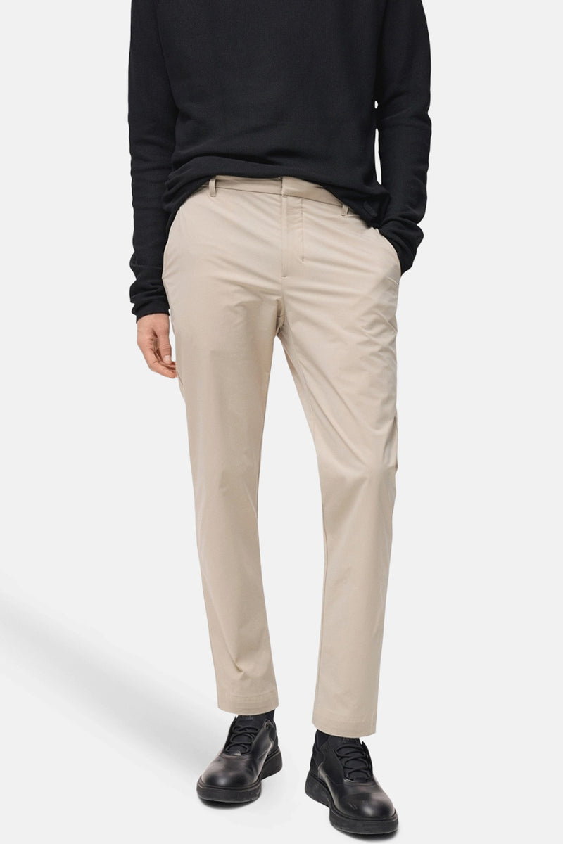 Beige broek van MANGO, gedragen met een zwarte trui en donkere leren schoenen.