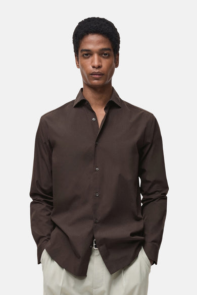 Bruin overhemd met lange mouwen van MANGO, open gedragen bij de hals en op een lichte broek.