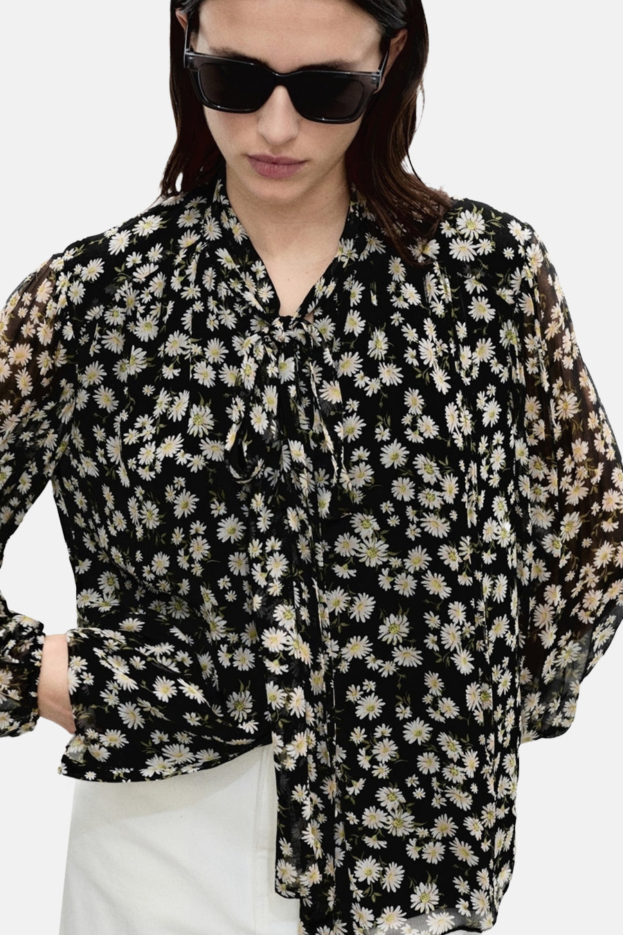 Zwarte blouse met lange mouwen van MANGO, madeliefjespatroon op doorschijnende stof, gedragen met een witte broek.
