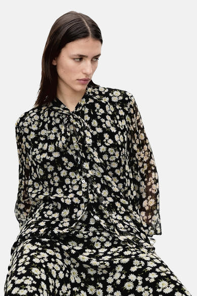 Zwarte blouse met lange mouwen van MANGO, versierd met een madeliefjesbloemenpatroon, met een strikkraag.