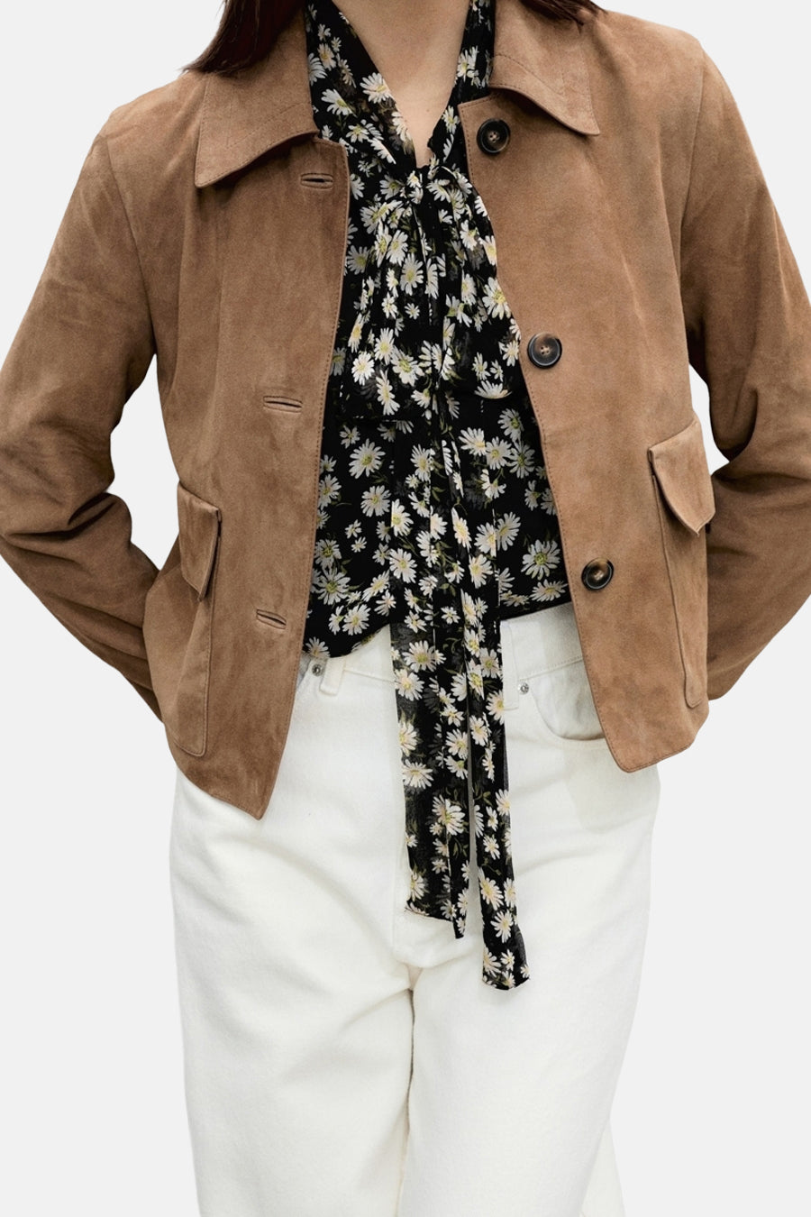 Zwarte blouse met lange mouwen, met witte madeliefjesprint, van MANGO, gedragen met een bruine jas en een witte broek