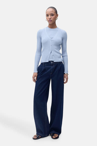 Blauwe cardigan van MANGO, gedragen over een bijpassend T-shirt en een wijde spijkerbroek, met zwarte sandalen.