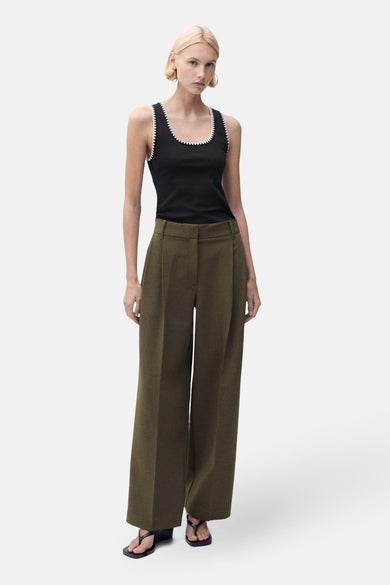 Débardeur noir par MANGO, avec bordure contrastante blanche, porté avec un pantalon ample vert olive.