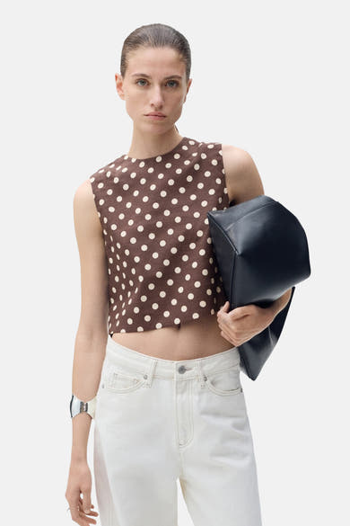 Chemisier sans manches brun à pois de MANGO, porté avec un jean blanc et un bracelet argenté.