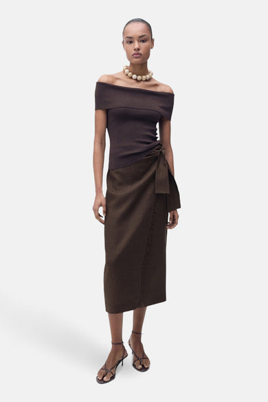 Bruine 3/4 rok van MANGO, met strikdetail aan de zijkant, gedragen met een beige top en ketting.