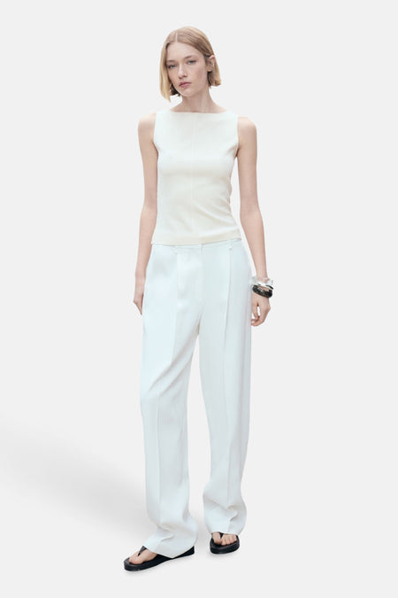 Ecru hemdje van MANGO, met een verticale naad middenvoor, gedragen met een witte broek en zwarte sandalen.