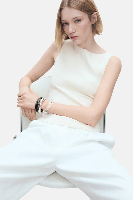Ecru hemdje van MANGO, gedragen met een wijde witte broek en decoratieve armbanden.