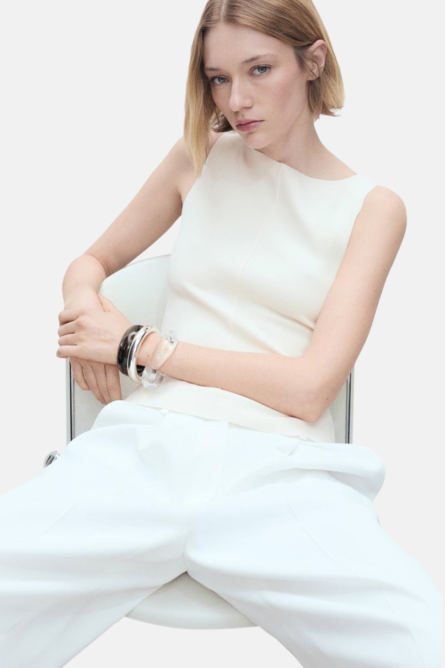 Ecru hemdje van MANGO, gedragen met een wijde witte broek en decoratieve armbanden.