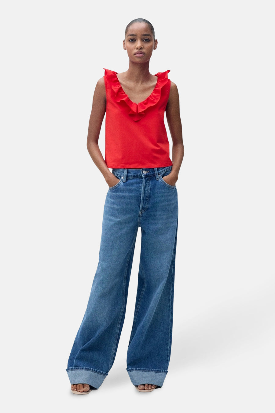 Rood mouwloos topje van MANGO, met een V-hals met ruches, gedragen met een wijde, hoge-taille spijkerbroek.