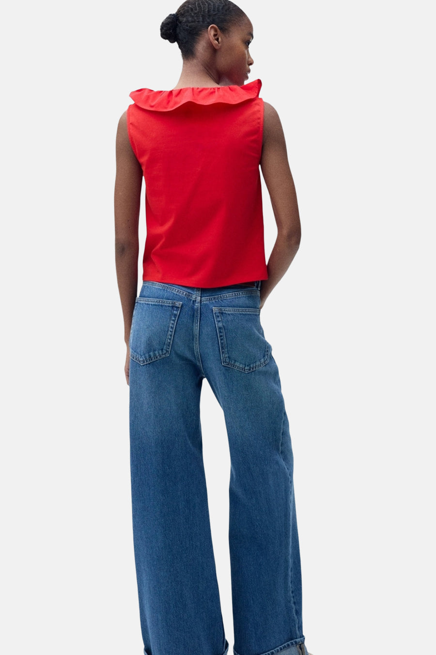 Top rouge sans manches de MANGO, avec volant rouge sur le col, porté avec un jean taille haute ample.