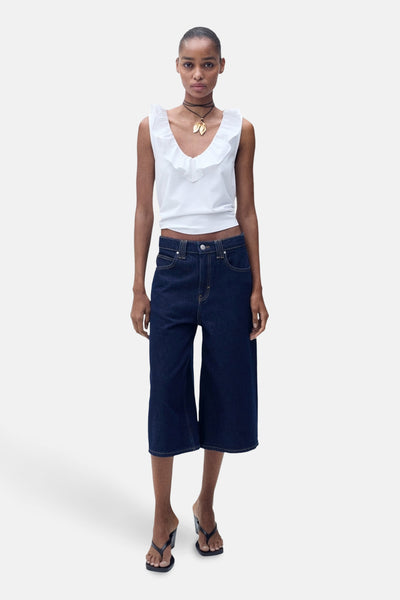Wit mouwloos topje van MANGO, met een geplooide V-hals, gedragen met een donkerblauwe korte broek.
