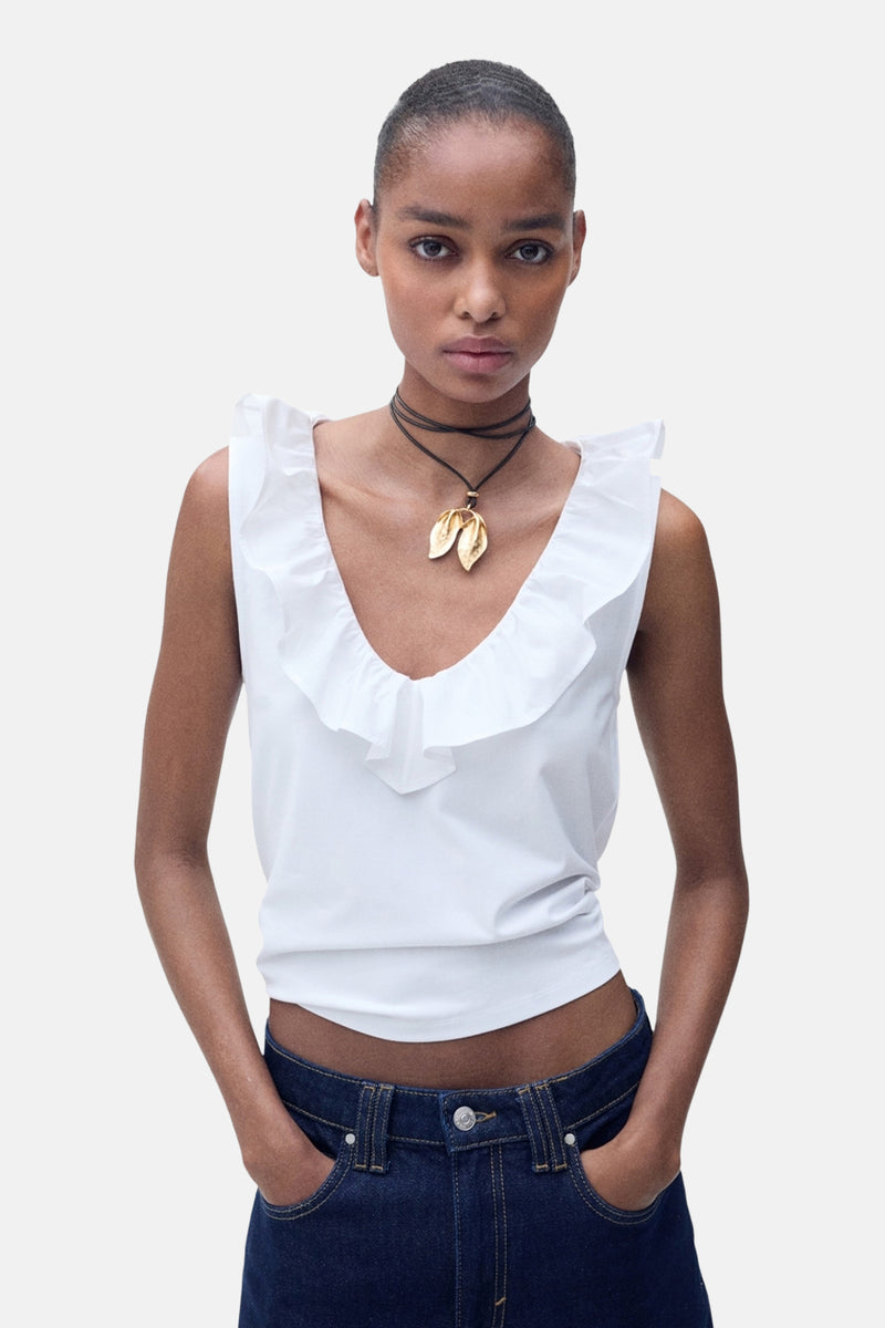 Wit mouwloos topje van MANGO, met ruche bij de halslijn en gedragen met een spijkerbroek en een ketting.