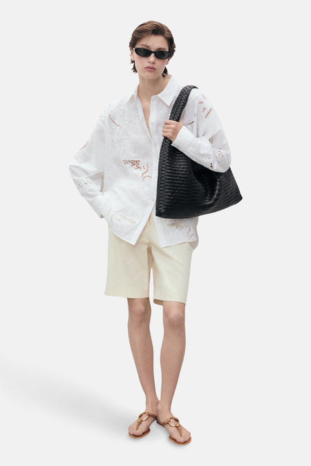 Wit overhemd met lange mouwen van MANGO, met bloemenborduursels en gedragen met een beige korte broek en sandalen.