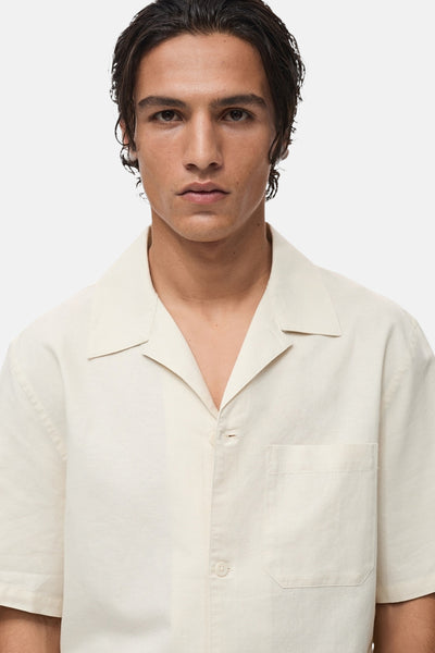 Chemise écru à manches courtes de MANGO, avec poche plaquée sur le devant, portée par un homme.