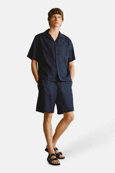 Chemise à manches courtes bleue de MANGO, portée avec un short assorti et des sandales noires.