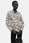 Wit overhemd met lange mouwen en zebraprint, van MANGO, gedragen met een zwarte broek.