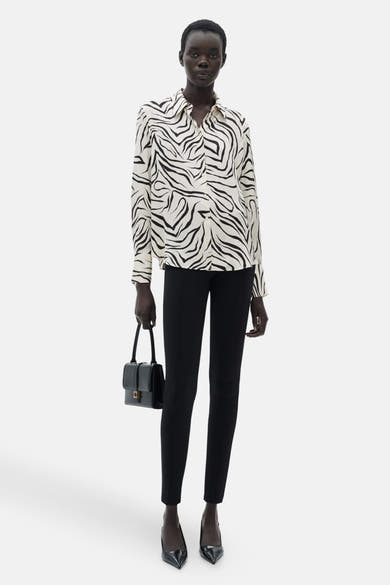 Wit overhemd met lange mouwen en zebraprint van MANGO, gedragen met een zwarte broek en zwarte lakpumps.