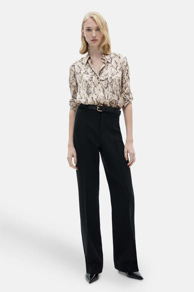 Bruine blouse met lange mouwen met slangenprint, van MANGO, gedragen met een zwarte broek en een riem.