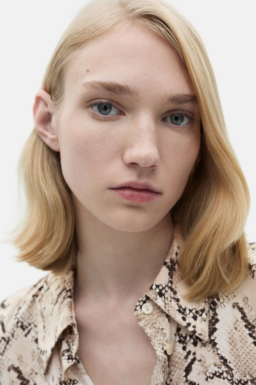Bruine MANGO-overhemd met lange mouwen, slangenprint op neutrale beige achtergrond.