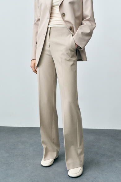 Pantalon de costume beige de MANGO, coupe droite, porté avec un blazer assorti et des chaussures blanches.