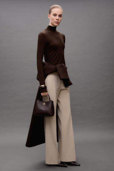 Pantalon de costume beige de MANGO, porté avec un haut marron et des chaussures en cuir.