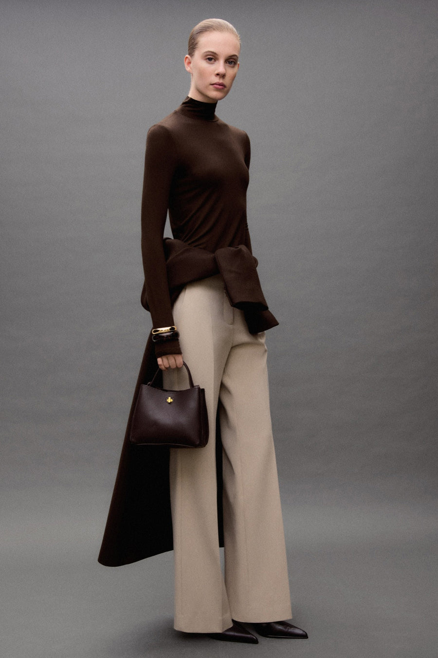 Pantalon de costume beige de MANGO, porté avec un haut marron et des chaussures en cuir.