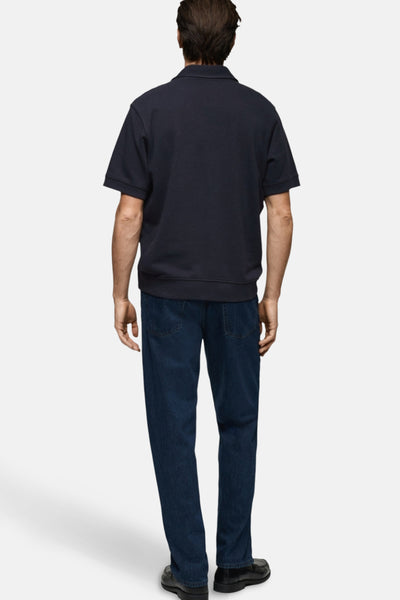 Polo bleu foncé par MANGO, porté avec un jean foncé et des chaussures noires, vue de dos.