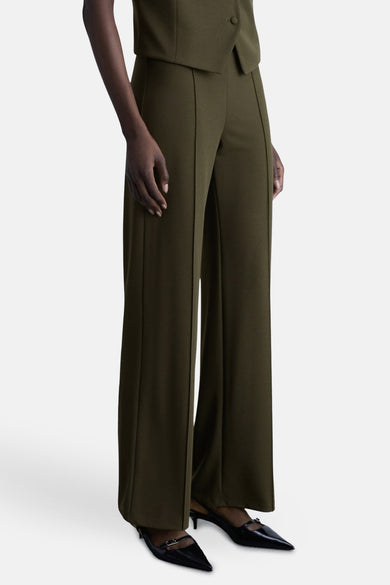 Kaki broek van MANGO met een centrale naad, gedragen met zwarte lakpumps.