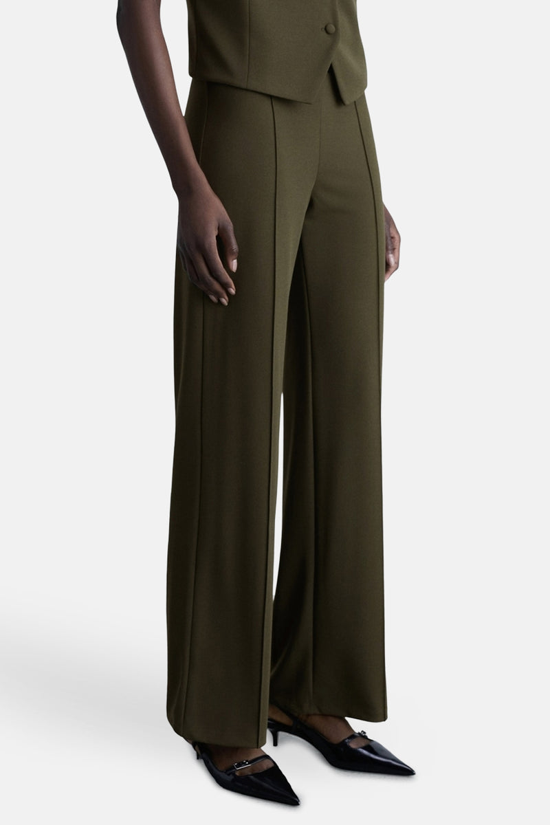Kaki broek van MANGO met een centrale naad, gedragen met zwarte lakpumps.