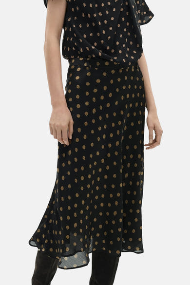 Lange veelkleurige rok van MANGO, met beige stippen op een zwarte achtergrond, gedragen met suède laarzen.