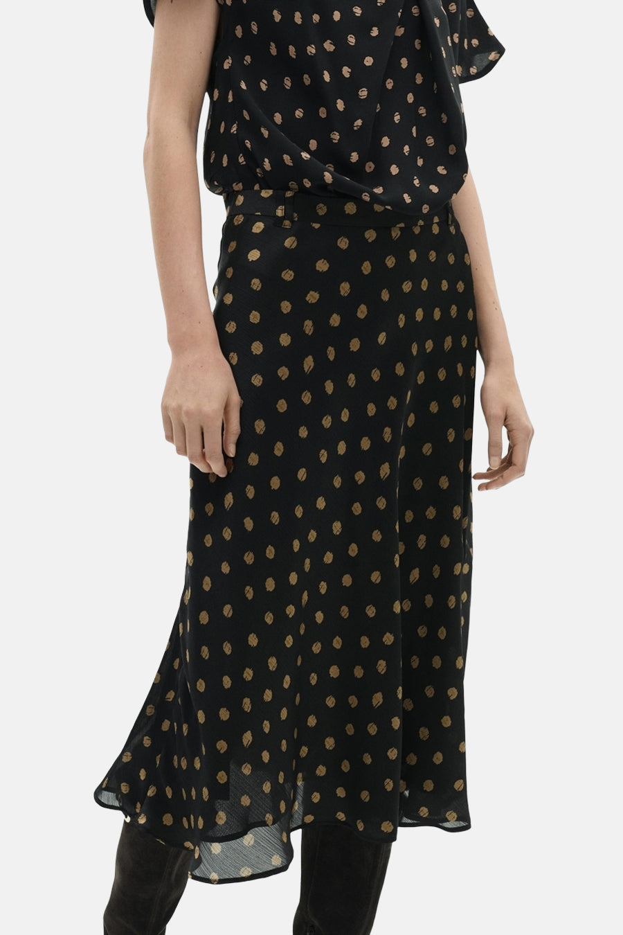 Lange veelkleurige rok van MANGO, met beige stippen op een zwarte achtergrond, gedragen met suède laarzen.