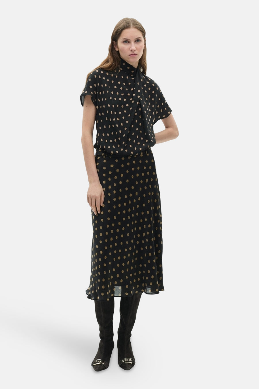 Jupe longue multicolore de MANGO, à pois beiges sur fond noir, portée avec des bottes en daim.
