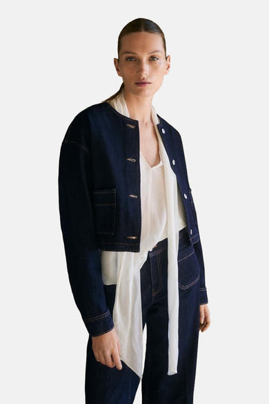 Blauwe spijkerblazer van Mango, gedragen met een witte geknoopte blouse en een bijpassende broek.