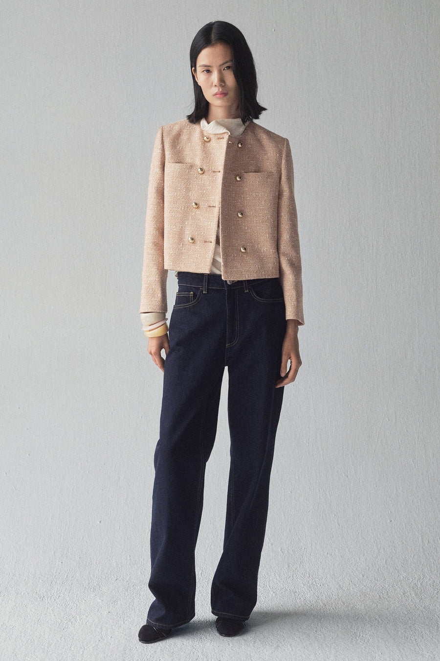 Beige blazer van MANGO, dubbelgeknoopt met gouden knopen, gedragen met een donkerblauwe jeans en zwarte schoenen.